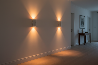 Pair of white cylindrical motion sensor night lights glowing warm amber in hallway