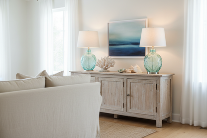 Pair of coastal nautical table lamps with blue-green glass bases on driftwood sideboard in coastal living room